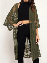 woman wearing an olive green lace kimono over a black crop top and black pants