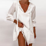 Woman wearing a white V-neck mini dress with tie detail and ruffled cuffs