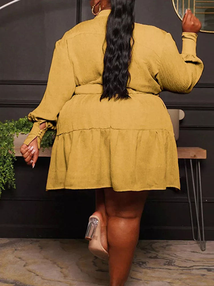 Rear view of a woman wearing a mustard yellow shirt dress with a belted waist and tiered hem.