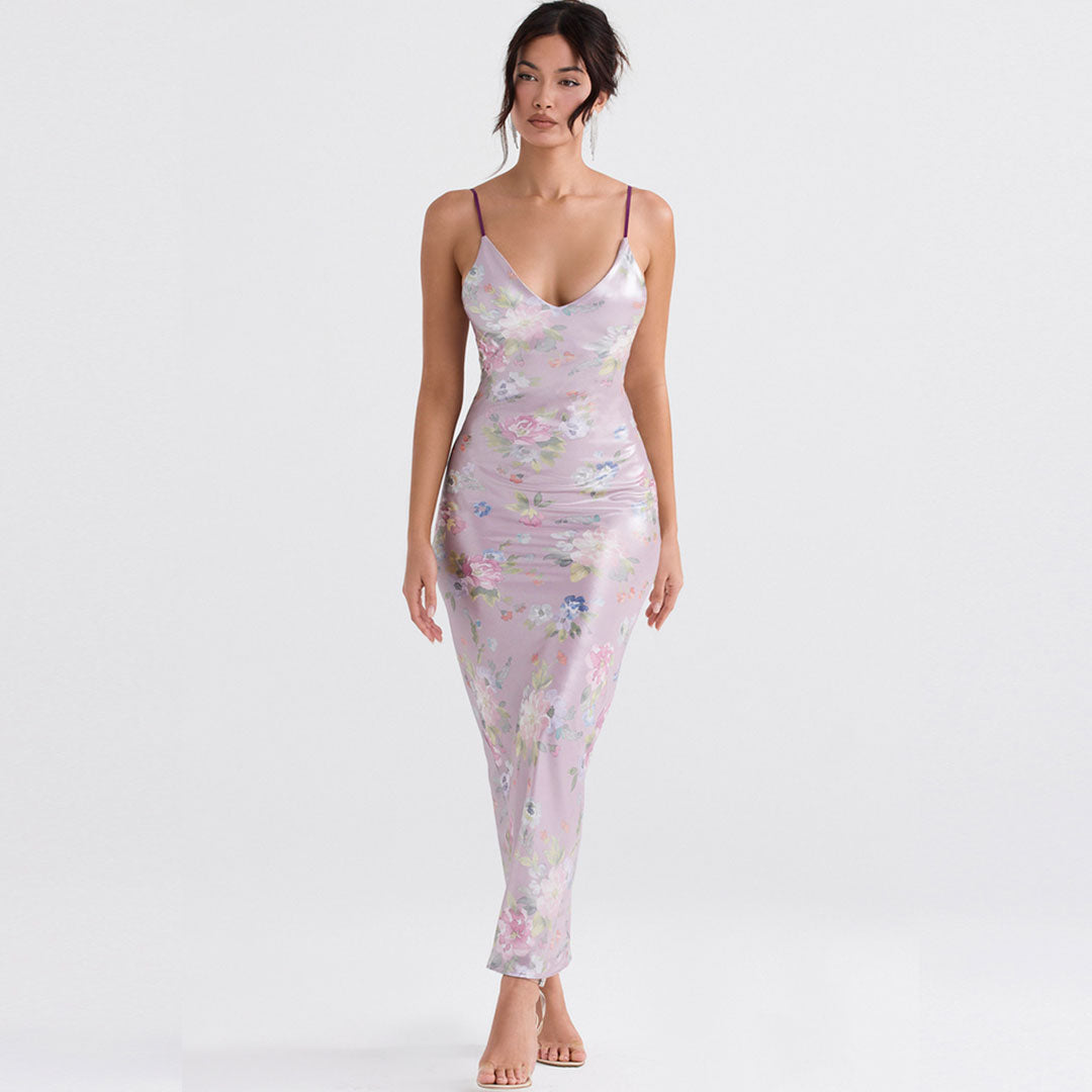 Woman wearing a long, floral print, lavender slip dress with spaghetti straps.
