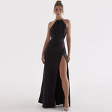 woman wearing a black floor-length halter dress with a high slit