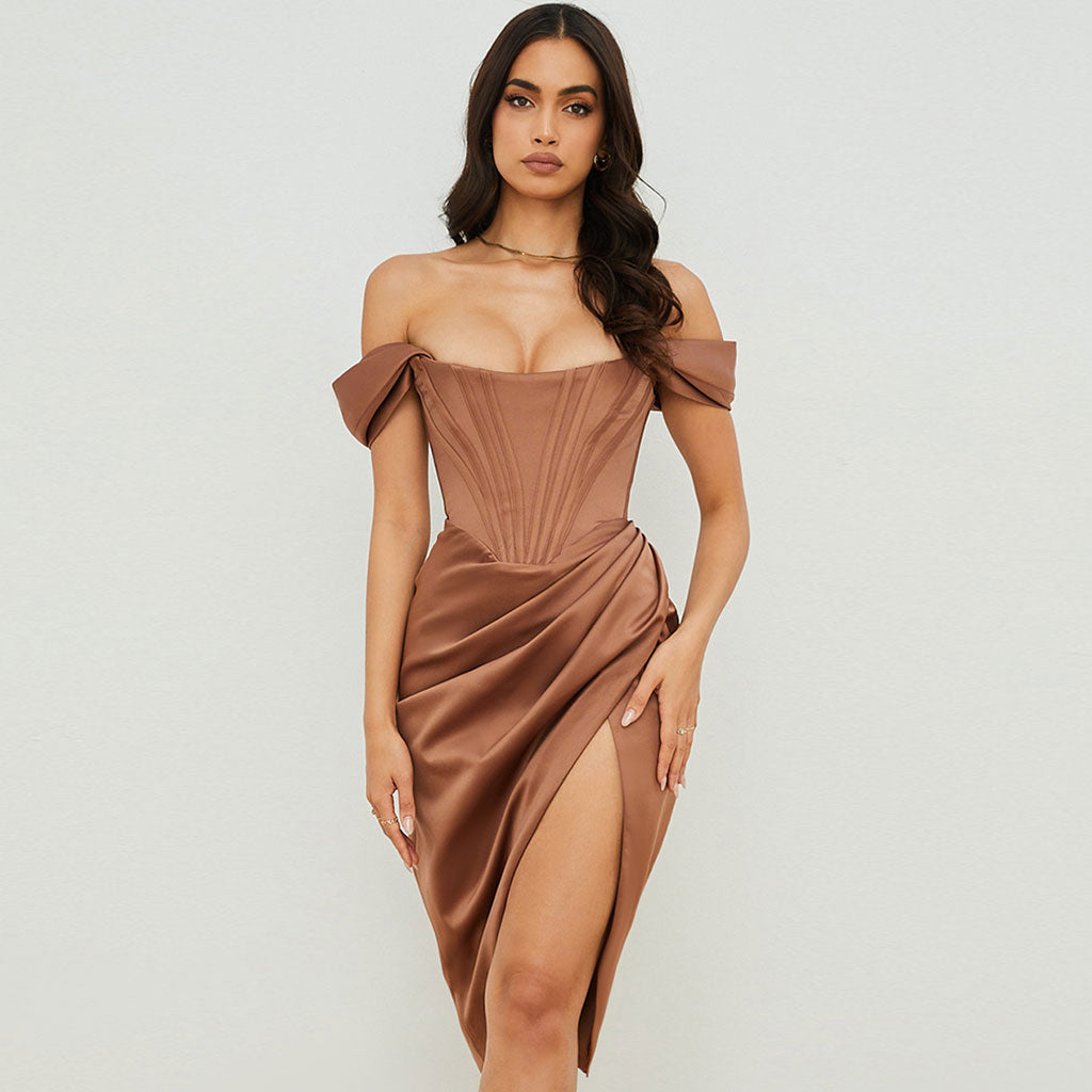 Woman wearing a brown off-the-shoulder satin dress with a structured bodice and high slit, standing against a white background.