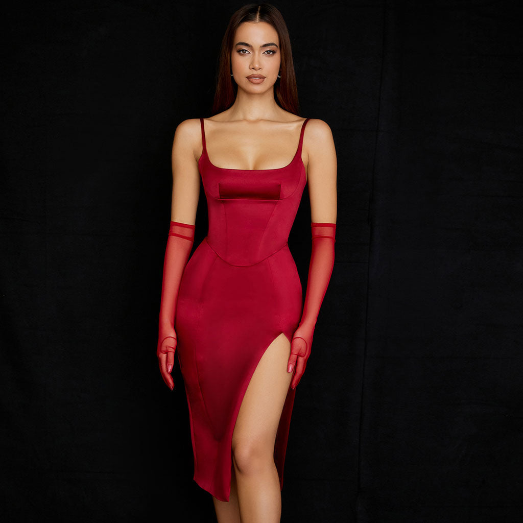 Woman in a red satin midi dress with a high slit and spaghetti straps.