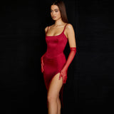 Side profile of a woman in a red satin sheath dress with a square neckline and a high slit.