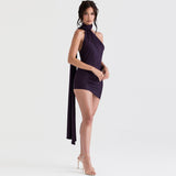 side view of a woman in a dark purple halter neck mini dress