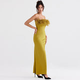 Side view of a woman in a yellow satin maxi dress with a feather trim bodice and spaghetti straps.