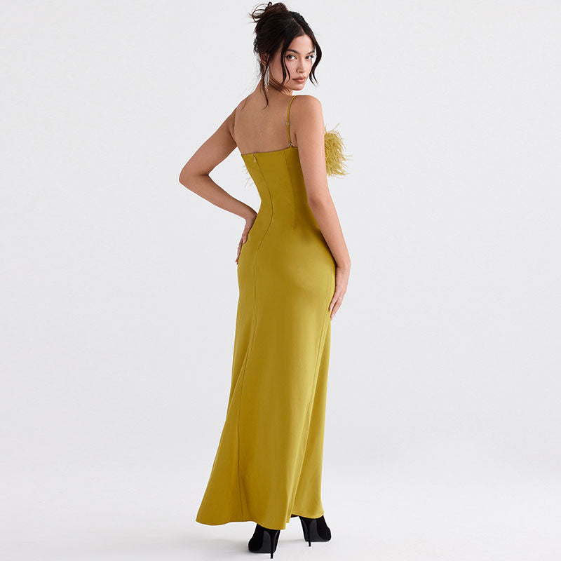 Back view of a woman in a yellow satin maxi dress with a feather trim bodice and spaghetti straps.