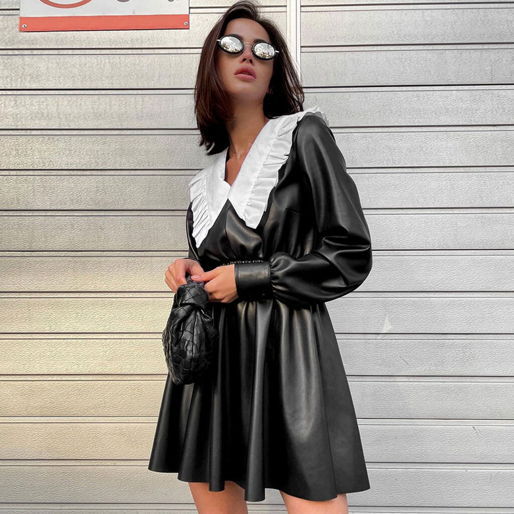 full body shot of a woman in a black faux leather dress with a white ruffled collar