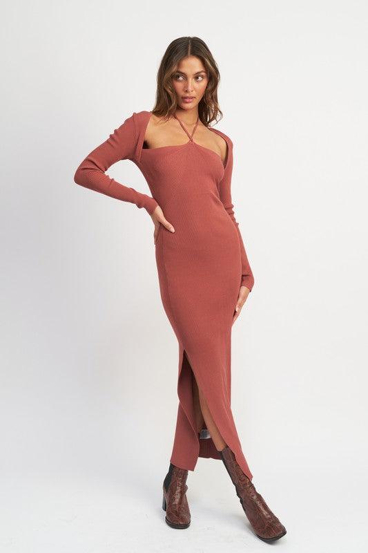 Woman in a terracotta ribbed knit maxi dress with a halter neckline and high slit, posing with hands on hips.