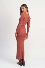 Back view of a woman wearing a terracotta ribbed knit maxi dress with a halter neckline and long sleeves.