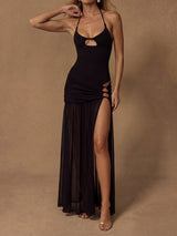 Woman wearing a black halter maxi dress with a cutout bust and a high slit skirt.