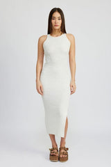Woman wearing a white ribbed knit midi dress with a high neckline and sleeveless cut, standing against a light grey background.