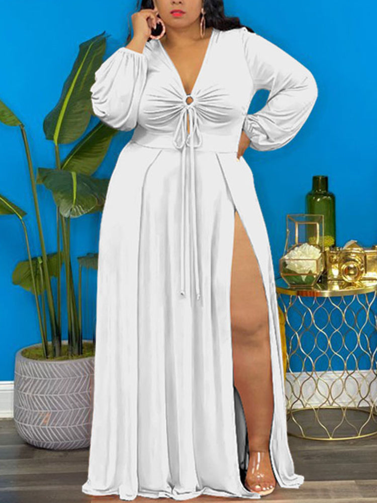 Woman wearing a white maxi dress with a deep V-neckline, drawstring detail, bishop sleeves, and a high slit.