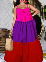 Woman wearing a vibrant, tiered maxi dress with spaghetti straps and a gathered neckline. The dress is color-blocked in bright pink, purple, and red.