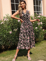 Woman in a black floral print midi dress with ruffled V-neck and tie waist, standing outdoors