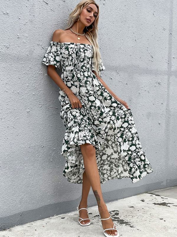 Woman leaning against a wall, wearing a floral print off-the-shoulder maxi dress with a ruffled hem.