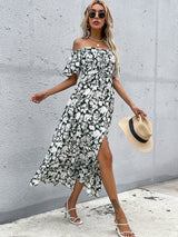 Woman in a floral print off-the-shoulder maxi dress with a thigh-high slit, walking outdoors.