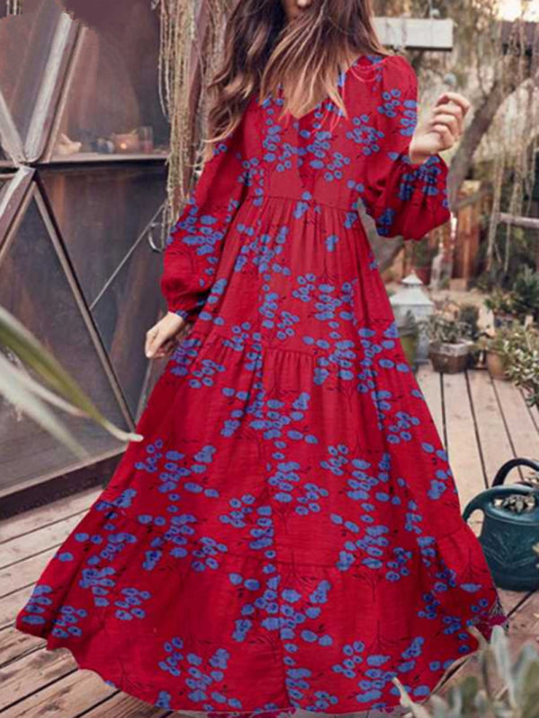 Woman wearing a long red floral maxi dress with bell sleeves on a wooden deck.