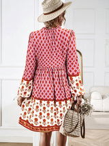 Woman with a straw hat wearing a pink and white floral print tiered mini dress.