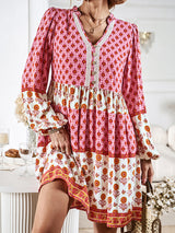 Woman holding a straw bag and flowers, wearing a pink and white tiered mini dress.