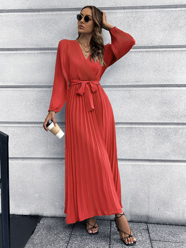 woman holding a coffee cup while wearing a red pleated maxi dress