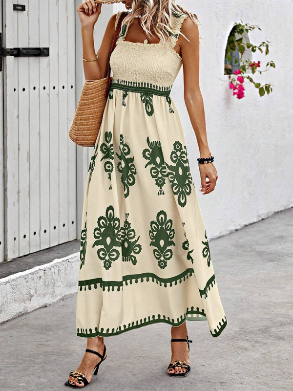 Woman wearing a cream and green floral print maxi dress with smocked bodice and square neckline, standing on a cobblestone path.