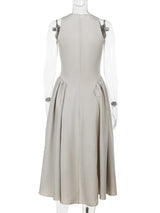 Mannequin displaying the back view of a beige sleeveless A-line dress with a keyhole neckline and a pleated skirt.