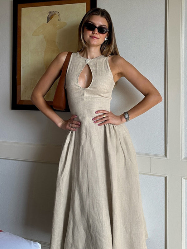 Woman wearing a beige sleeveless A-line dress with a keyhole neckline and a pleated skirt, accessorized with sunglasses and a brown shoulder bag.