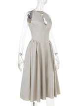 Mannequin displaying the side view of a beige sleeveless A-line dress with a keyhole neckline and a pleated skirt.