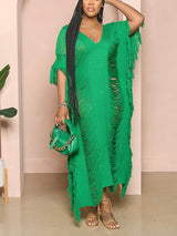 Woman wearing a green distressed knit maxi dress with fringe detailing and a V-neck.