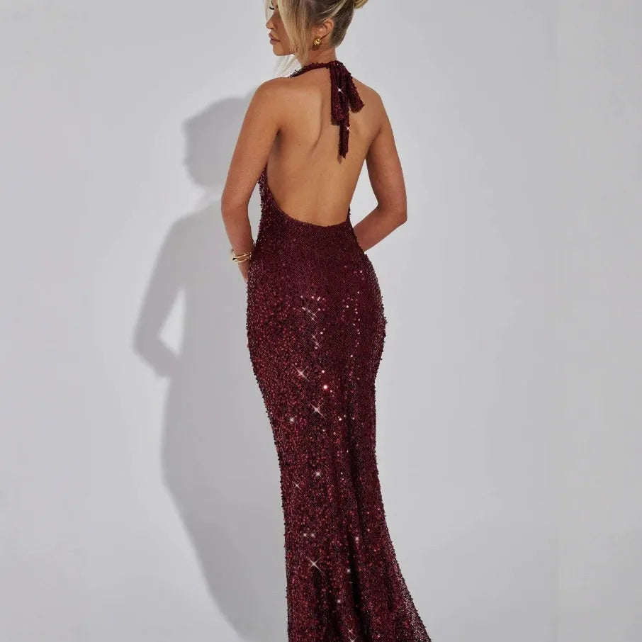 Back view of a woman wearing a long burgundy sequined halter dress
