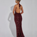 Back view of a woman wearing a long burgundy sequined halter dress