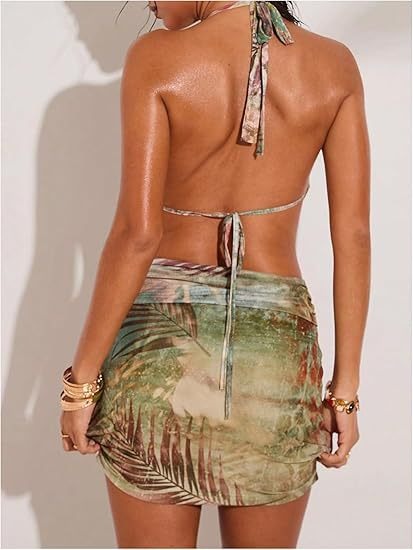 Back view of a woman in a tropical print halter neck dress with a tie closure and a ruched mini skirt.