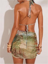 Back view of a woman in a tropical print halter neck dress with a tie closure and a ruched mini skirt.