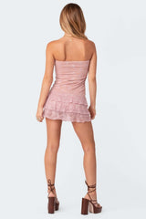 back view of a woman in a pink strapless lace mini dress