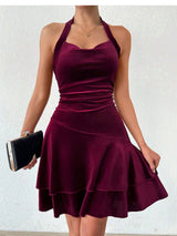 Woman holding a black clutch while wearing a maroon velvet halter dress