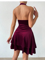 Back view of a woman wearing a maroon velvet halter dress with a layered skirt