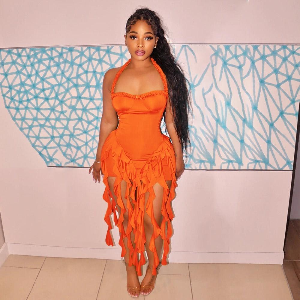 Woman wearing an orange halter dress with ruffled trim and a fringed hem