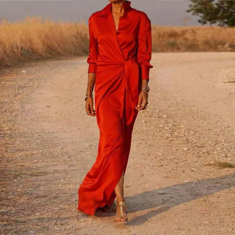 Woman wearing a long red satin dress with a V-neck and long sleeves.
