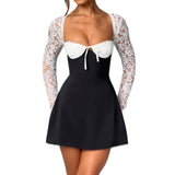 Woman wearing a black and white mini dress with white lace sleeves and a white bow detail, front view