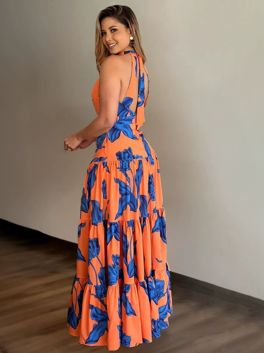 Woman wearing a teal and red tropical print maxi dress with a high slit and one-shoulder design.
