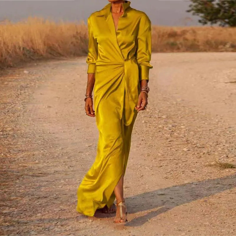 Woman wearing a long yellow satin dress with a V-neck and long sleeves.