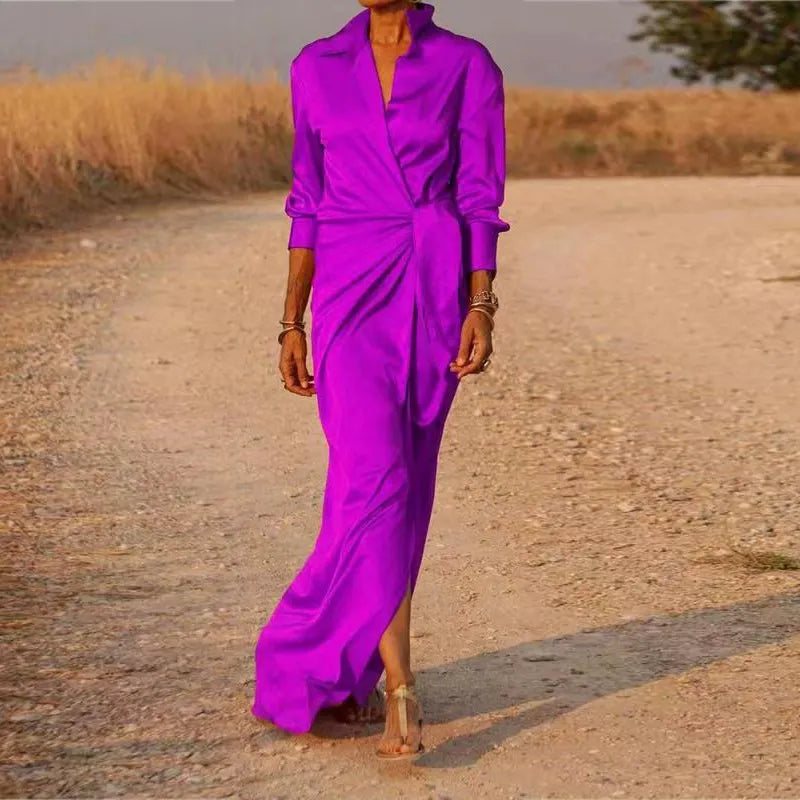 Woman wearing a long purple satin dress with a V-neck and long sleeves.