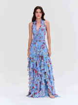 Woman wearing a light blue floral print halter neck ruffled gown with a thigh-high slit.