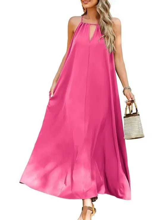 Woman wearing a bright pink sleeveless maxi dress with a halter neckline and keyhole cutout, holding a small woven bag, standing against a white background.