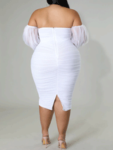 Rear view of a woman in a white off-the-shoulder ruched midi dress, showing zipper detail.