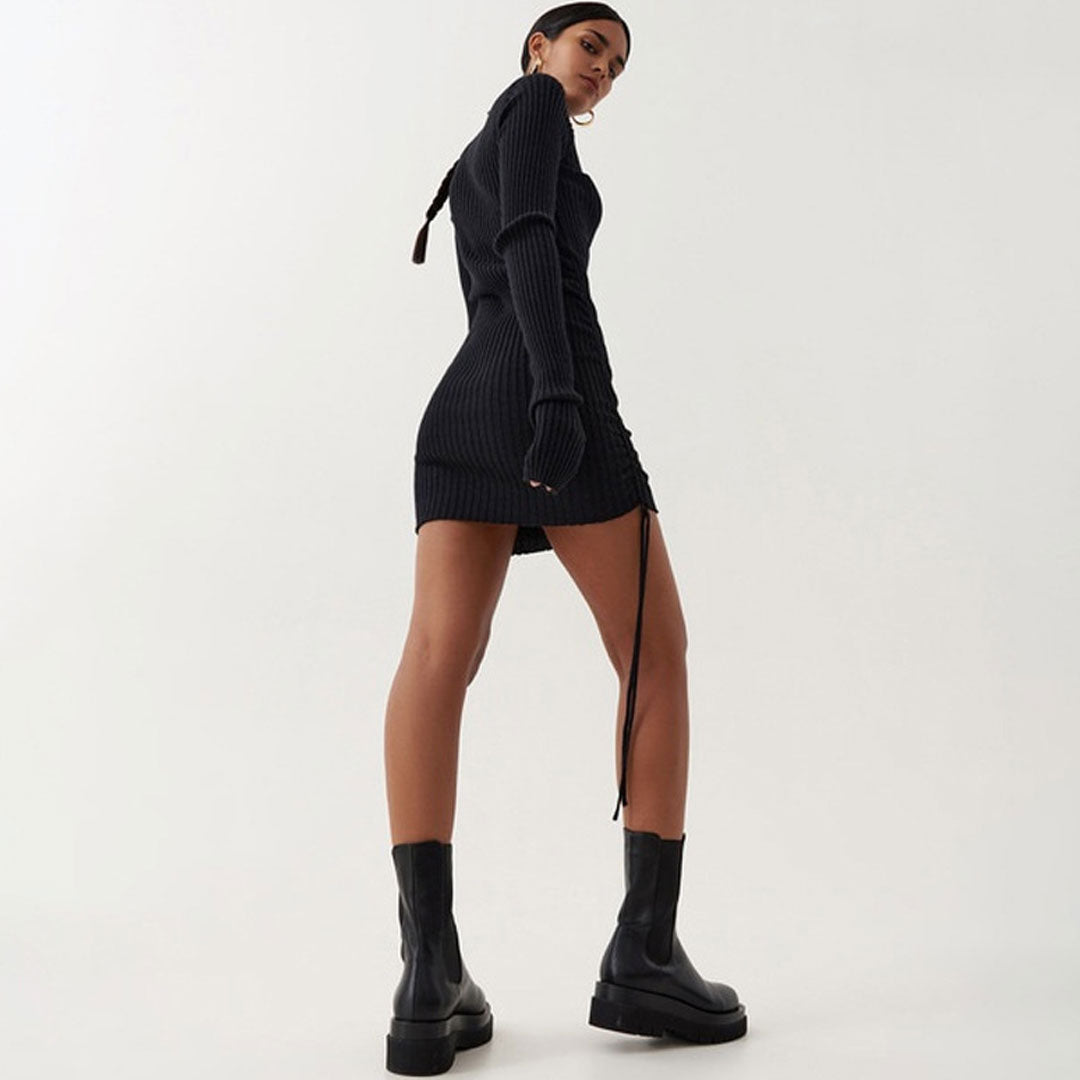 Rear view of a woman in a black ribbed knit turtleneck mini dress.