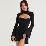 Woman in a black dress with a cutout and bell sleeves, posing against a white background.