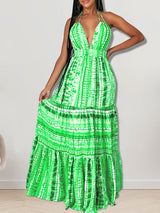 Woman wearing a long green tie-dye halter neck dress with a tiered skirt
