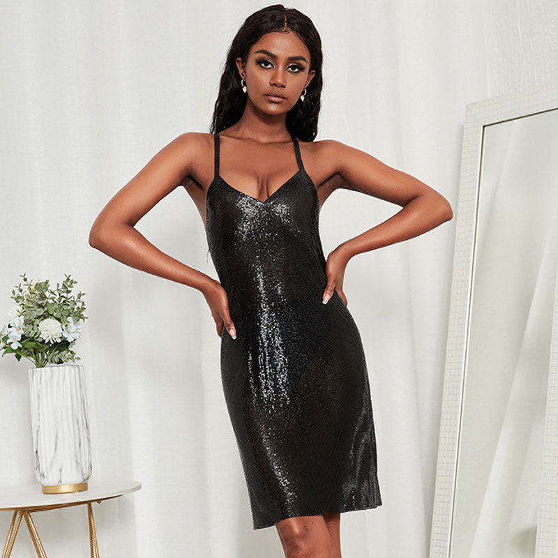 Woman wearing a black sequined sheath dress with spaghetti straps and a v-neck.